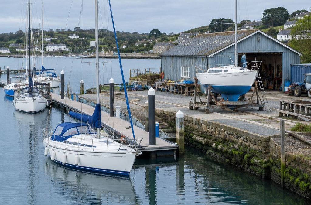 Sailing boats moored beside a working marina and boatyard workshop