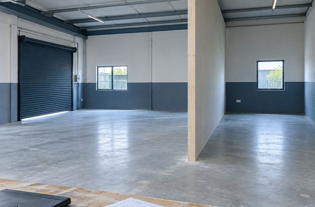 Light-industrial unit interior divided by a new partition wall, with floor plans in the foreground